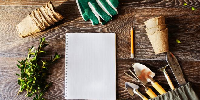 Note book, peat pots and tools laid out for spring garden planning. 