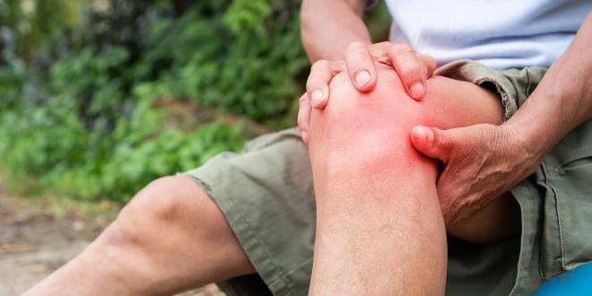 an older hiker grabbing his knee in pain