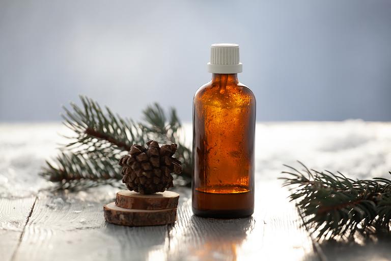 an aromatherapy bottle surrounded by springs of pine and pinecones