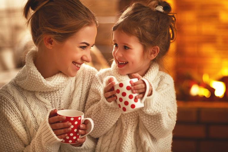 a mother and child drinking tea by the fireplace