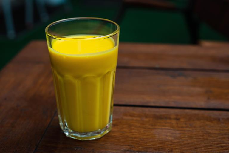 a tall glass of a creamy mango smoothie